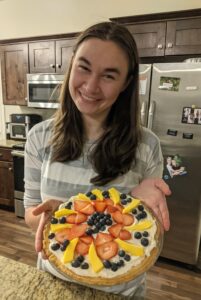 Woman presenting a fruit pie.