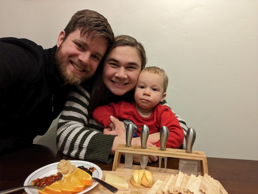 Young Family sitting behind a charcuterie board.