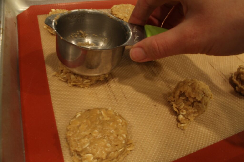 Flattening cookie dough with measuring cup.