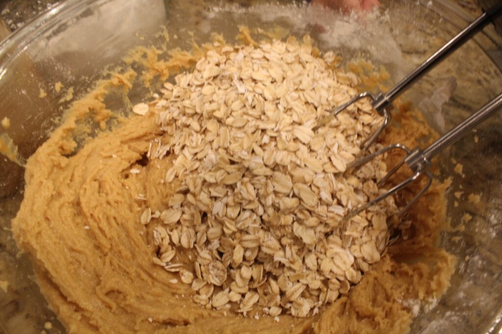 Oats ready to be mixed into natural peanut butter cookie dough.