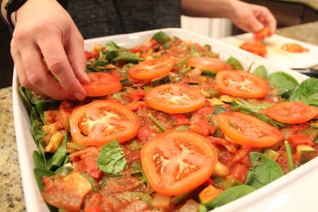 Topping veggie lovers lasagna with sliced tomatoes