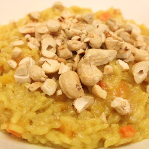 Bowl of curried butternut squash risotto topped with cashews.