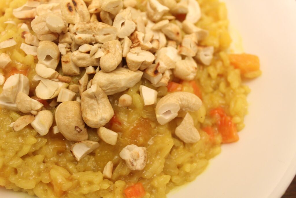 Close up of curried butternut squash risotto topped with cashews.