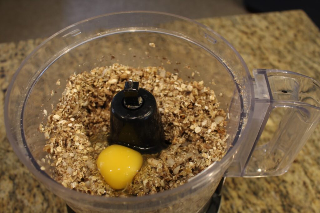 Minced ingredients with an egg on top in a food processor.