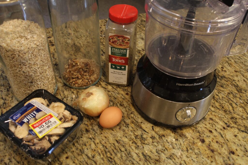 A food processor with Ingredients set out for mushroom meatballs.