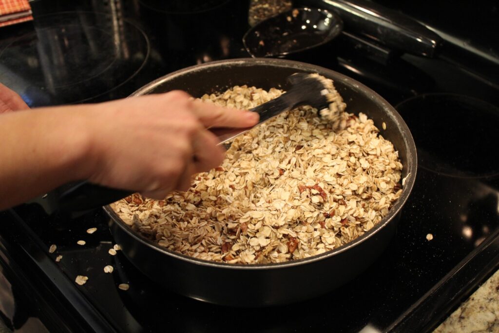 Stirring together uncooked granola in a pan.