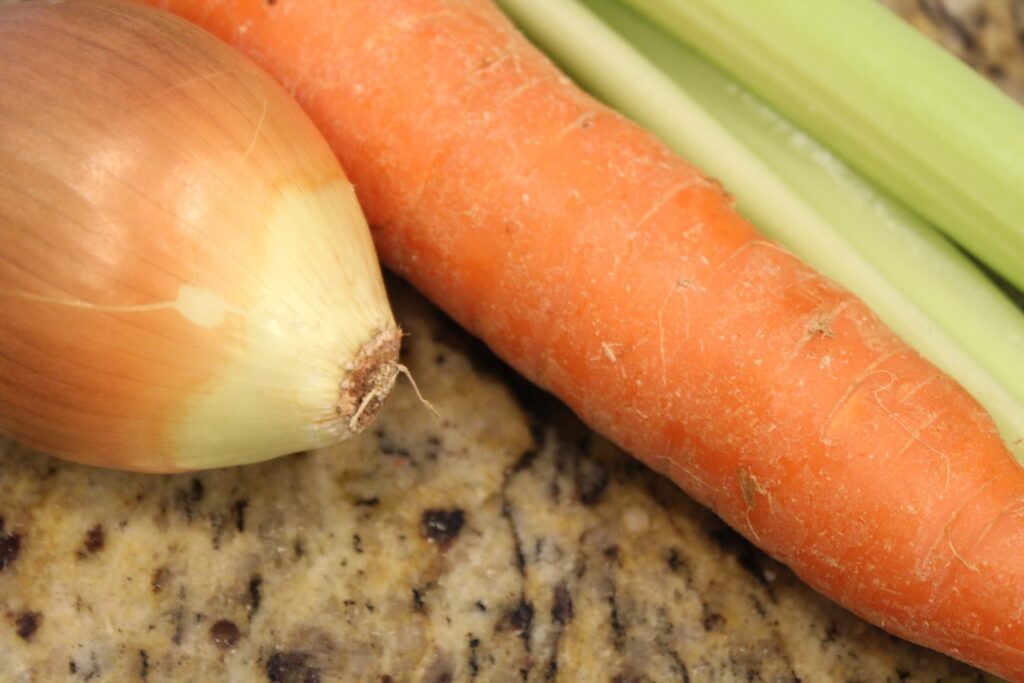 Close up of an onion, carrot, and celery.