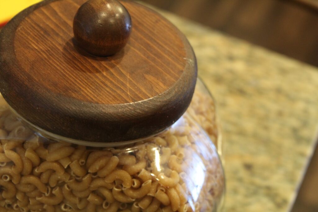 A jar full of uncooked macaroni noodles.