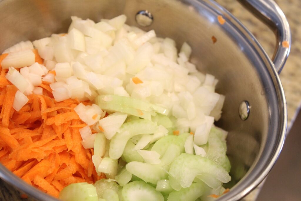 Grated carrot and thinly diced celery and onions in a small pot.