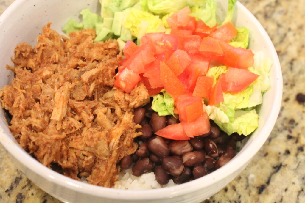 Slow cooker Mexican sweet pork in a bowl with beans and vegetables.