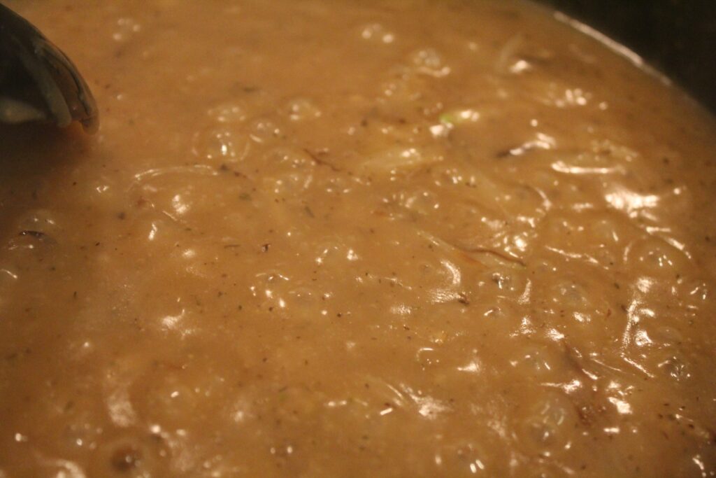 Onion gravy boiling in a frying pan.