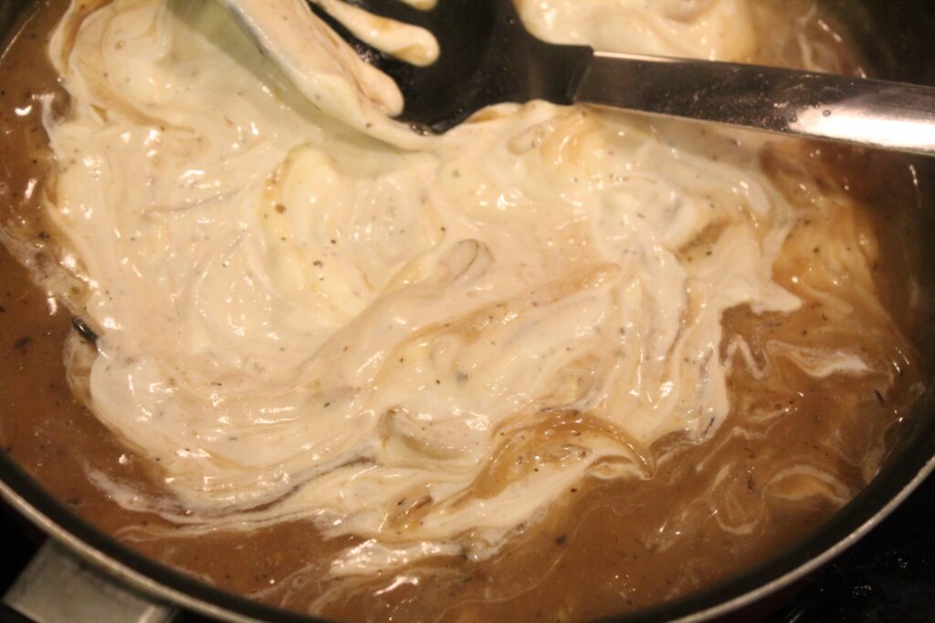 Mixing sour cream into onion gravy.