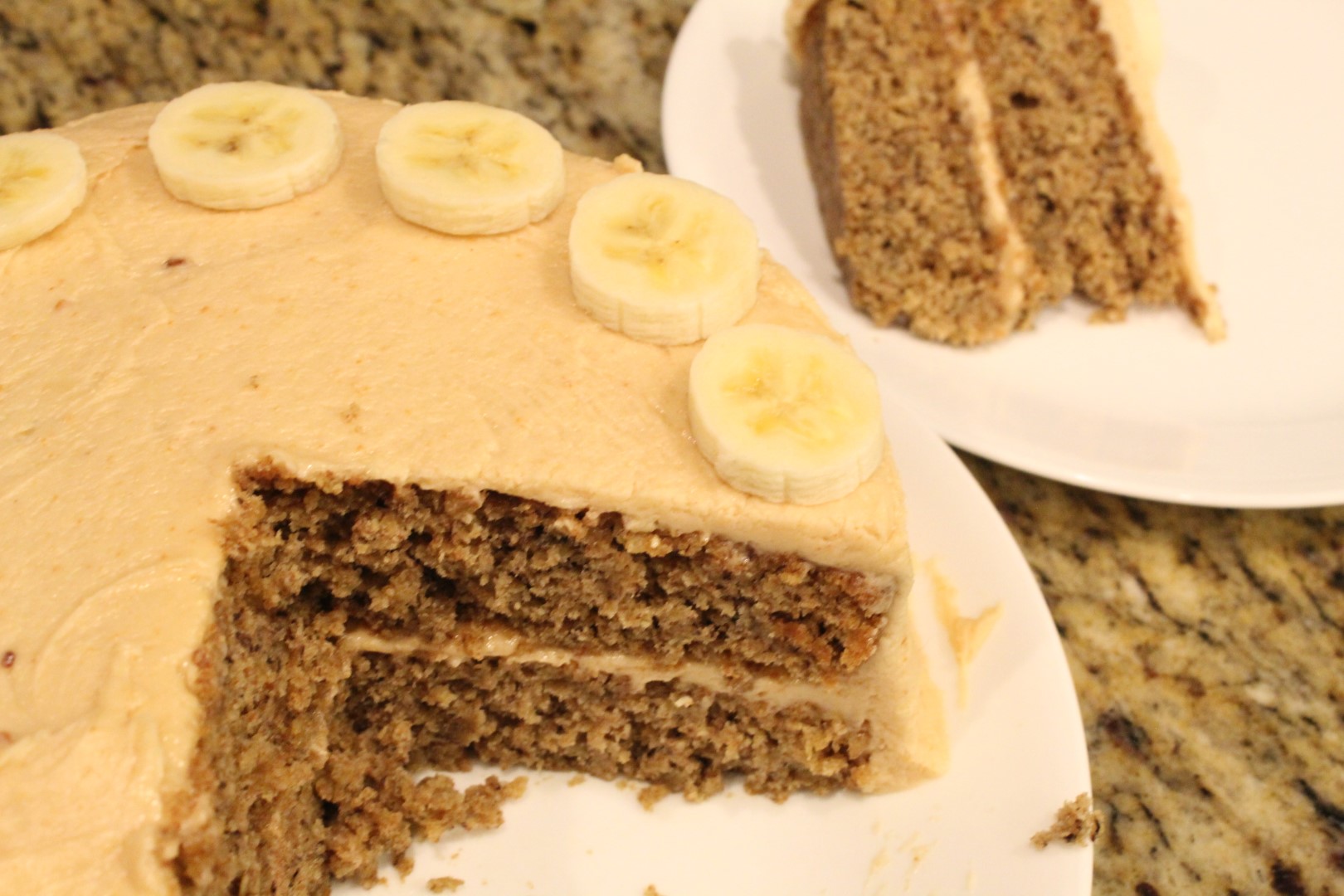 Sliced banana oat cake with peanut butter frosting topped with banana slices
