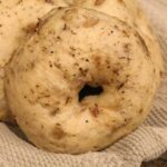 close up of homemade onion bagels in a towel lined bowl.