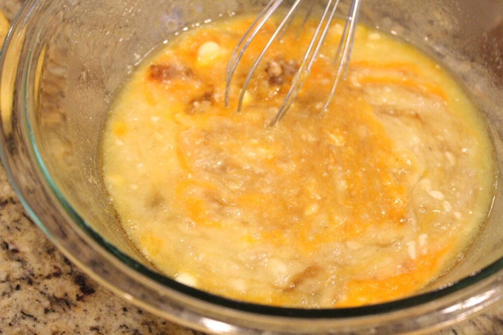 Sugar being mixed into banana butter and egg mixture.