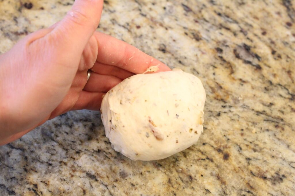 shaping onion bagel dough by rolling against the counter.