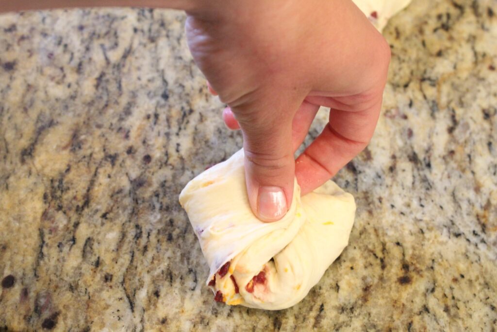 shaping orange cranberry bagel dough by bringing the corners into the middle.