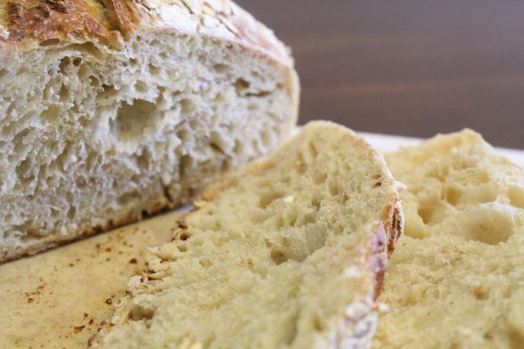 Sliced loaf of sourdough honey oat bread.