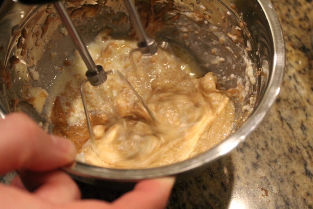 Mixing butter, cream cheese, and peanut butter with a hand mixer.