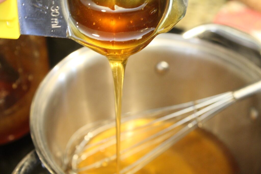 Adding honey to a pot.