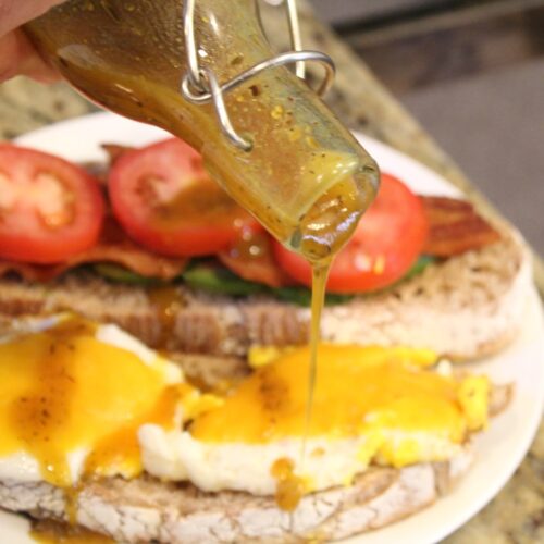 Pouring Honey mustard vinaigrette onto a sandwich.