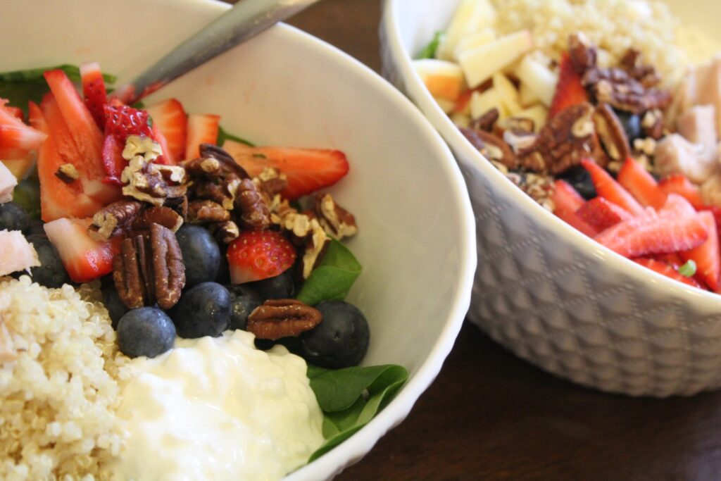 Spinach salad topped with strawberries, blueberries, quinoa, pecans, cottage cheese, and chopped turkey.