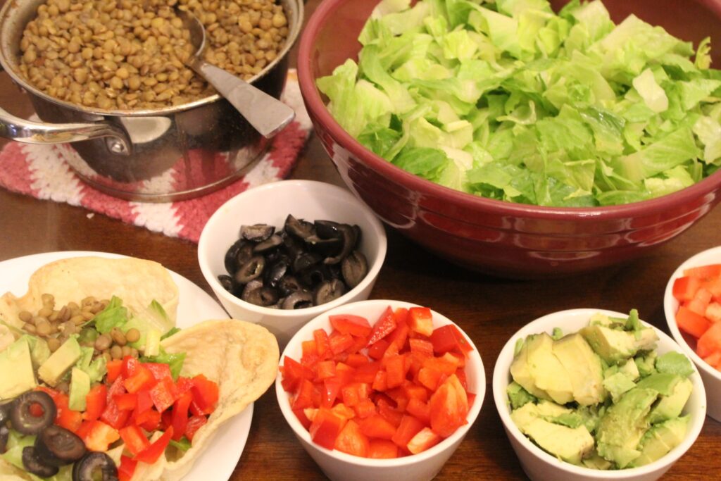 Taco seasoned lentils and a spread of taco salad ingredients in separate bowls.