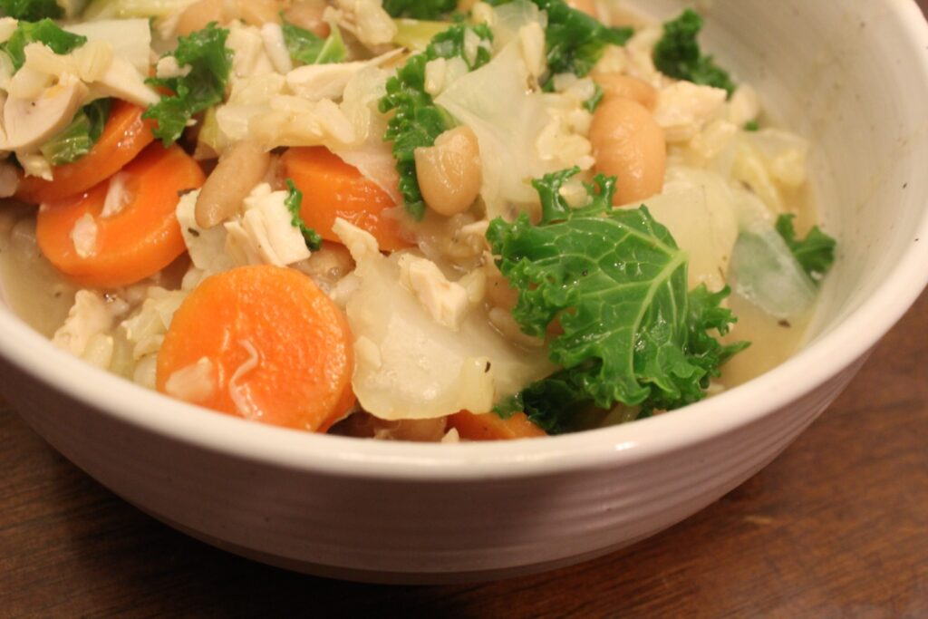 Bowl of soup with rice beans carrots and kale.