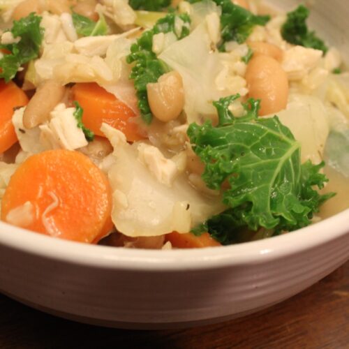 Bowl of soup with rice beans carrots and kale.