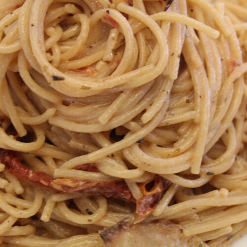 Twirled Home-made dried tomato pasta close up.