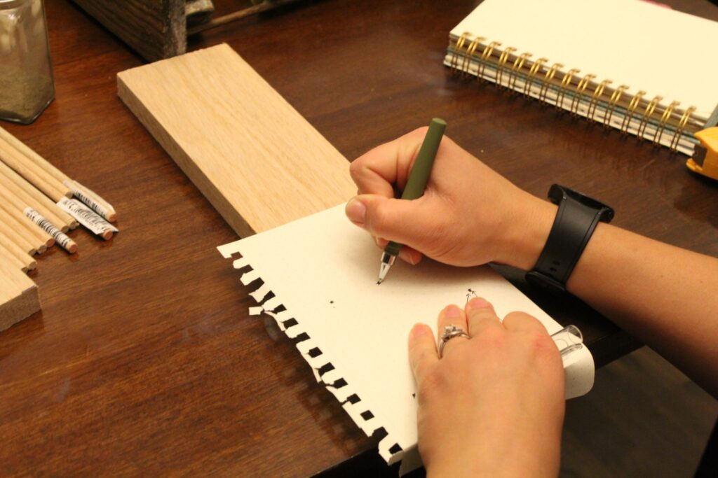 Marking where to drill holes on a plank of wood.