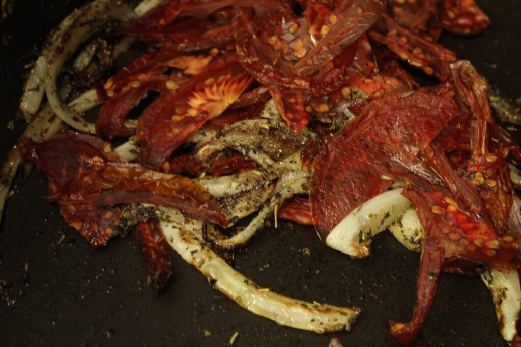 Dried tomatoes onions and seasonings cooking in a pan.