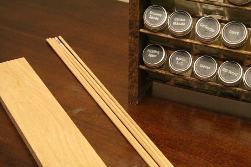 Wood plank and dowels next to a completed spice rack