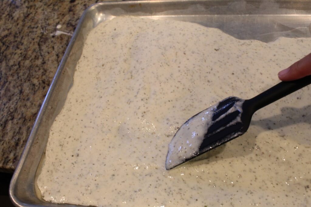 spreading cracker batter onto preheated oiled pan.