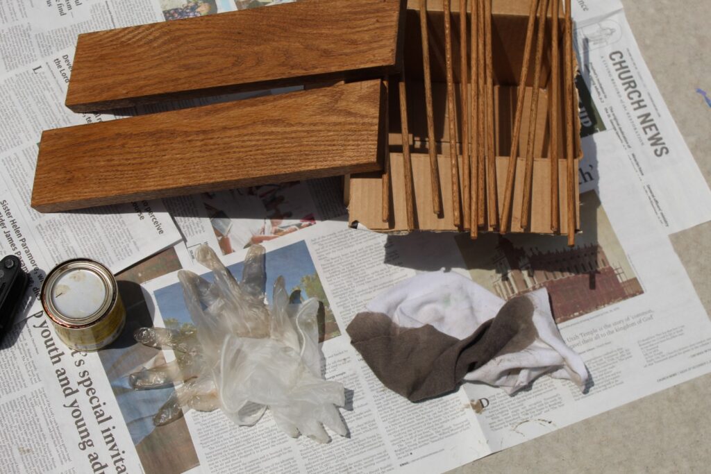 Stained wooden planks and dowels set out on a card board box and news paper to dry.