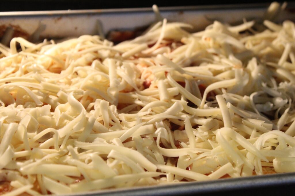 enchiladas topped with cheese in an oven.