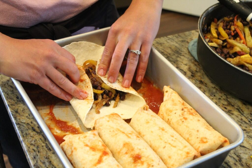 Folding up a black bean fajita enchilada.