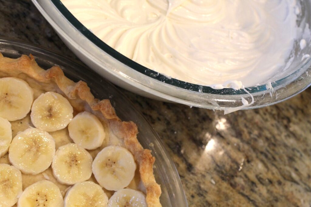 Bowl of cream cheese pie filling next to a baked piecrust layered with banana.