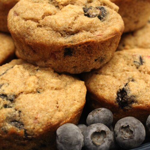 Whole wheat banana berry muffins on a plate with blueberries