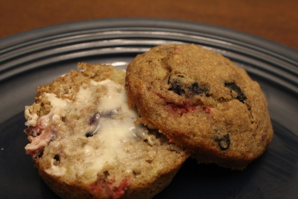 Whole wheat banana berry muffin spread with butter. 