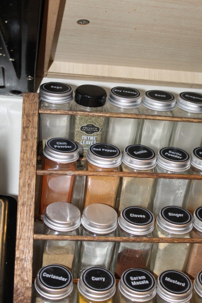 Low profile spice rack full of spices under a kitchen cabinet.