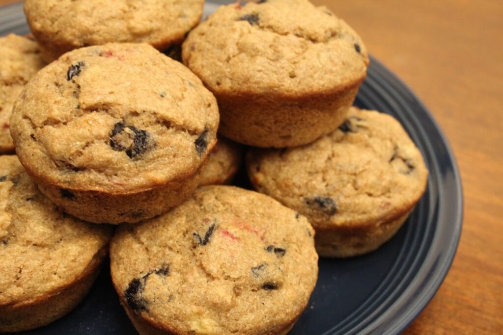 a stack of whole wheat banana berry muffins on a blue plate.