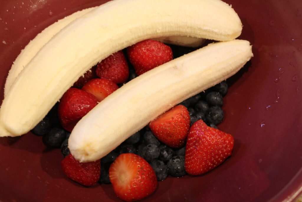  bowl of bananas, strawberries and blueberries.