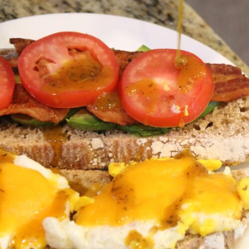 Vegetable topped breakfast sandwich being drizzled with honey mustard.