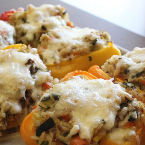 Vegetable and rice stuffed peppers topped with cheese.