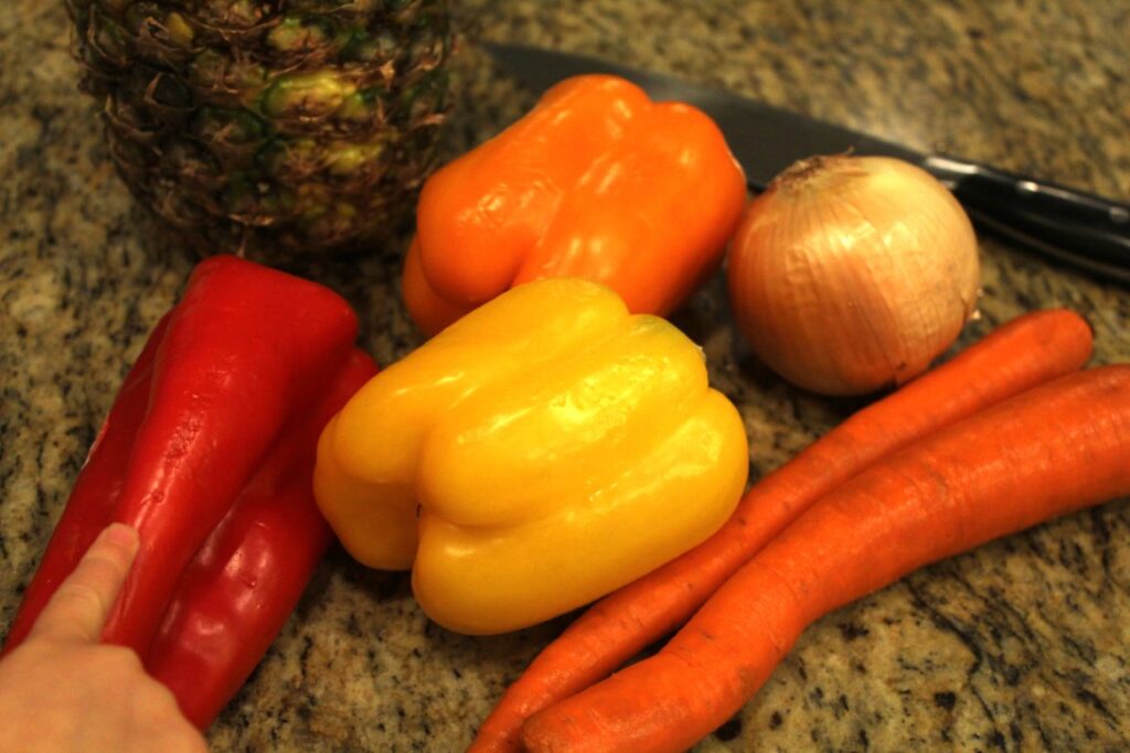 Peppers, carrots, an onion, and a pineapple.