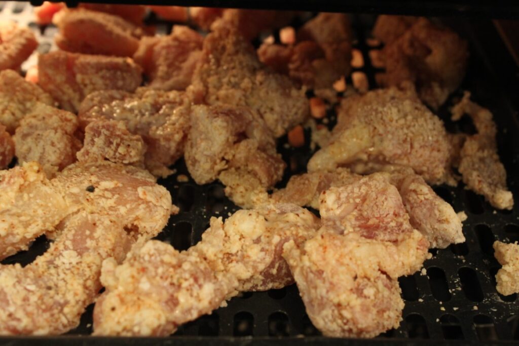 Putting coated chicken pieces into the air fryer.