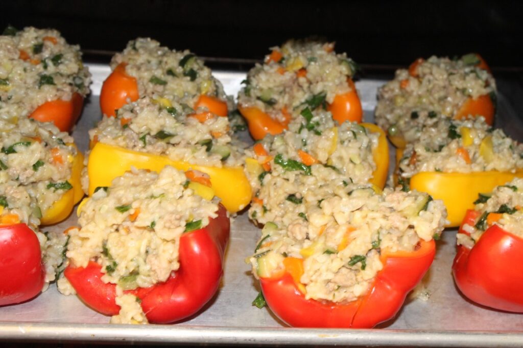 Half bell peppers stuffed with rice and veggie mixture in the oven.