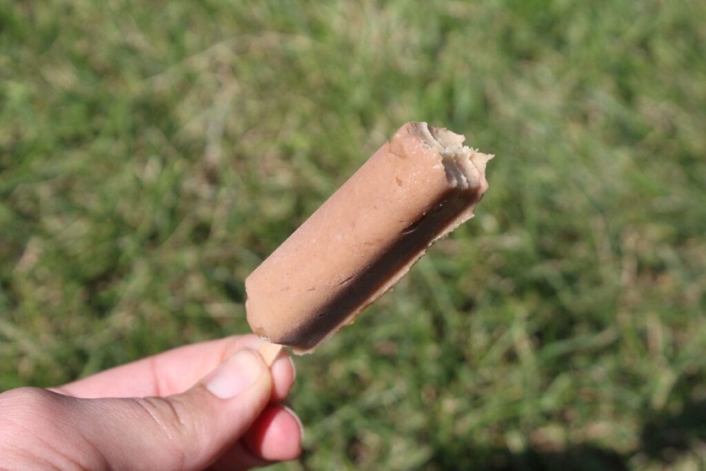 2 ingredient peanut butter banana popsicle with a bite taken out of it. 