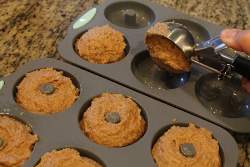 Scooping batter into silicone doughnut molds.